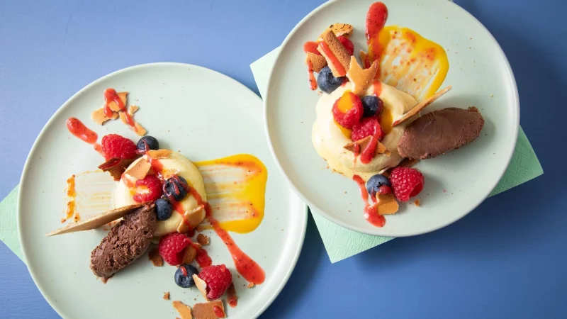 Sieht aus wie ein Bagel aus Eis: In sogenannte Savarin-Formen wird das Mangoeis gefüllt und gefroren. Die Mitte wird mit Fruchtigem gefüllt, dazu einen Klecks Schokoladenmousse, Mango- und Erdbeerpüree drunter und drüber streichen. - © Christin Klose/dpa-tmn