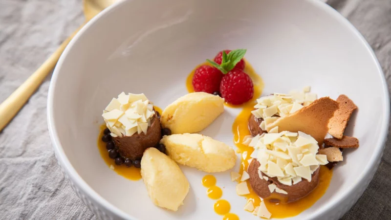 Dessert-Teller mit Schokoladen- und Mango-Mousse auf Mangopüree. Getoppt wird alles mit Eiswaffelsplittern, Schokoraspeln, Himbeeren und Minzblättern. - © Christin Klose/dpa-tmn