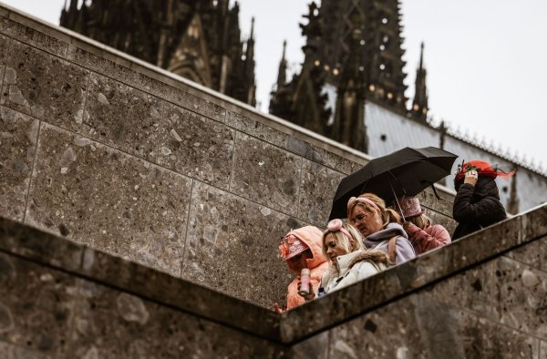 Karnevalistinnen feiern im Februar 2024 mit Regenschutz am Kölner Dom. (Archivbild) - © Oliver Berg/dpa