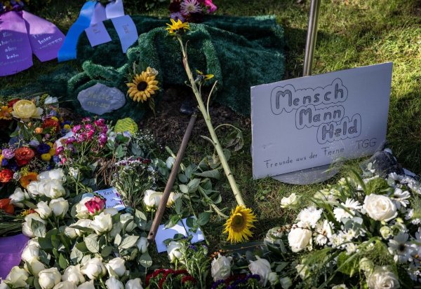 Blumen und ein Plakat mit der Aufschrift «Mensch, Mann, Held» liegen am Grab von Malte. - © Bernd Thissen/dpa/Archivbild