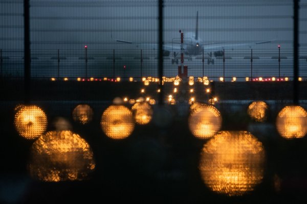 Ein Flugzeug landet hinter Signallichtern auf einem Flughafen. - © Sebastian Gollnow/dpa/Symbolbild