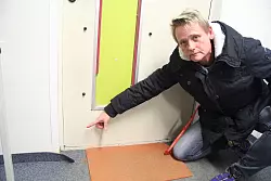 Aufl&ouml;sungserscheinungen: Daniela Niemann deutet auf den sich abl&ouml;senden Teppichboden. Die Scheibe, die mal im T&uuml;rausschnitt war, ist schon lange defekt, der Ersatz wird mit viel Silikon, Metall-Leisten und Schrauben an seinem Platz gehalten. &Uuml;berall in den Lohfeld-Containern wird versucht, den Verfall durch Flickschusterei aufzuhalten. - &copy; Dieter Asbrock