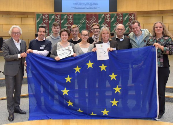Mit dem EU-Banner: (von links) Europaminister Dr. Stephan Holthoff-Pförtner gratuliert Nadir Kouri, Enrico Gomig, Laureen Hannig, Jonah Tappe, Ayleen Brandt, Michaela Gelke, Christiane Höke, Bernd Bretthauer-Aue und Fabian Sürken. Judith Schilling von der EU-Kommission Bonn freut sich für die Gesamtschule. - © Land NRW/W. Meyer