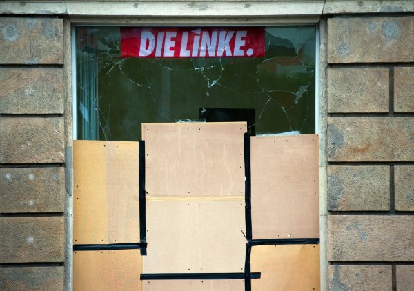 Das Fenster an einem Büro der Linkspartei ist nach einem Anschlag zerborsten und mit Holzplatten gesichert (Archivbild). - © Arno Burgi/dpa
