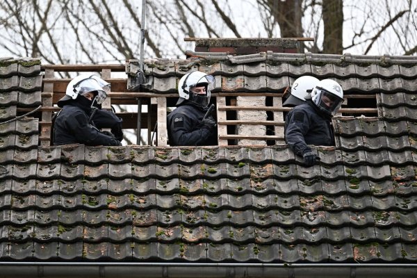 Polizisten schauen aus dem Dach eines besetzten Hauses am dritten Tag der Räumung in Lützerath. - © Federico Gambarini/dpa