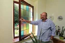 Uwe Bader öffnet das alte Buntglasfenster im Flur. Für akzeptable Wärmedämmwerte ist es zum Dreischeiben-Isolierglas umgerüstet worden. - © Bernhard Preuss