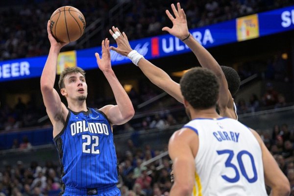 Franz Wagner (l/22) von Orlando Magic setzt Jordan Poole (hinten rechts) und Stephen Curry (30) von den Warriors zum Wurf an. - © Phelan M. Ebenhack/AP/dpa