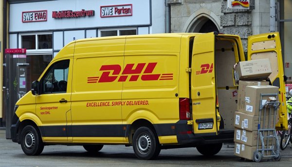 Ein Zustellfahrzeug von DHL steht an einer Straße. Der Bonner Logistiker hat in seinem Stammgeschäft - der Brief- und Paketbeförderung in Deutschland - bessere Geschäfte gemacht. - © Martin Schutt/dpa