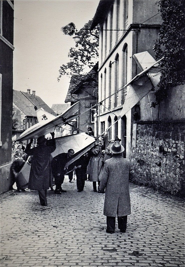 Eine spektakuläre Situation spielte sich vor dem langen Gottfried, rechts, in den 1930-er Jahren ab. Segelflugschüler hatten ein Flugzeug in einer Werkstatt gebaut und transportierten es zum Flugplatz - hochkant durch die enge Stelle der Hauptstraße. Im Vordergrund: Fritz („Tempo“) Drewes. - © Repro: Horst Biere