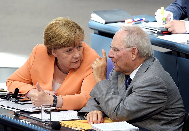 Die damalige Bundeskanzlerin Angela Merkel und der damalige Bundesfinanzminister Wolfgang Schäuble unterhalten sich 2015 im Bundestag in Berlin. - © Rainer Jensen