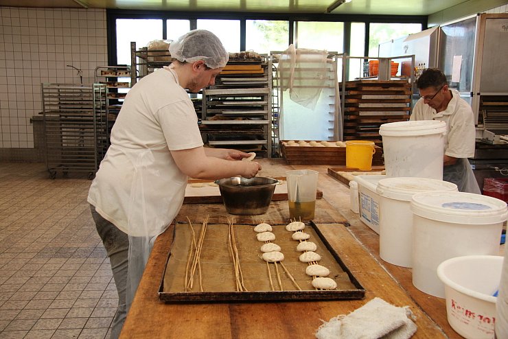 Bäckergeselle Pascal Pohlmann taucht die fertig geformete Teigware durchs Wasserbad und platziert sie zum Backen auf Roggenstroh. - © Jana Beckmann