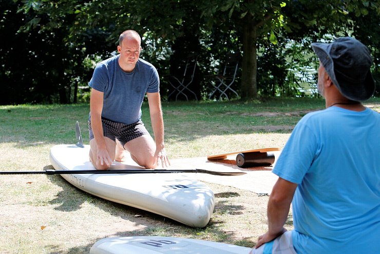 Bevor es beim Stand-Up-Paddling ins Wasser geht, wird an Land das Aufstehen auf dem Brett geprobt. - © Daniel Peters