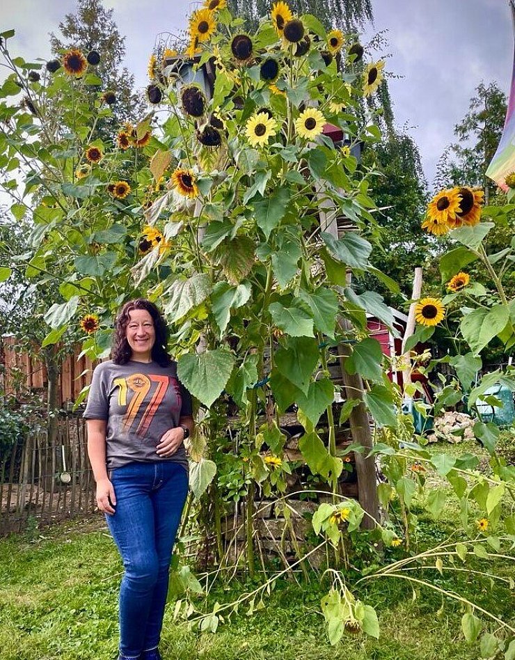 Christina Stannek und der von Sonnenblumen gesäumte Lebensturm im Garten der Familie. - © Jörg Stannek