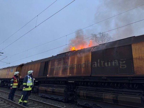 Flammen lodern auf einem Bauzug bei Porta Westfalica. Das sorgt für Umleitungen und Behinderungen im Bahnverkehr. - © Dominik Duensing/Feuerwehr Porta/dpa