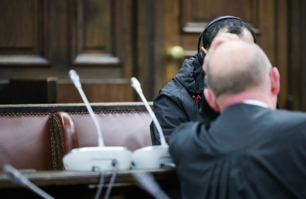 Einer der beiden Angeklagten (verdeckt) spricht mit seinem Anwalt Hannes Linke vor Prozessbeginn im Gerichtssaal des Strafjustizgebäudes. - © Christian Charisius/dpa-Pool/dpa