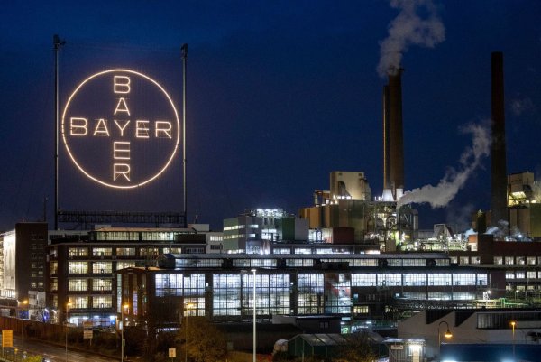 Das Bayer Kreuz, das Logo des Unternehmens, leuchtet auf dem Werksgelände von Bayer in Leverkusen. - © Thomas Banneyer/dpa
