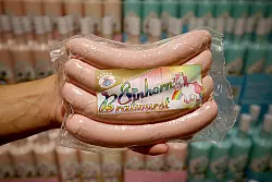 Einhorn Bratwurst hält ein Mitarbeiter in einem Supermarkt in der Hand. - © dpa
