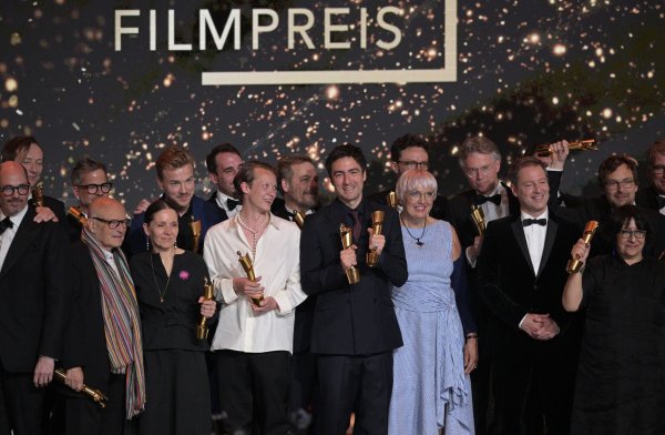 Zusammen mit Kulturstaatsministerin Claudia Roth (im blau-weiß gestreiften Kleid) stehen die Preisträger des Deutschen Filmpreises auf der Bühne. - © Hannes P. Albert/dpa