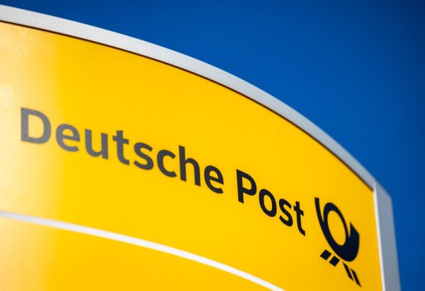 Ein Hinweisschild der Deutschen Post steht vor der Zentrale der Deutschen Post. - © Thomas Banneyer/dpa