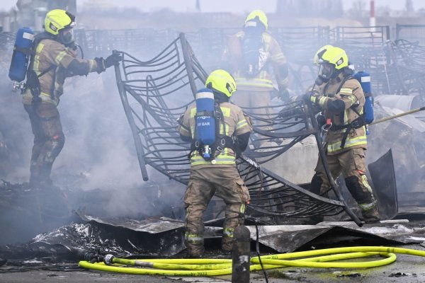 Feuerwehrmänner löschen die letzten Brandstellen in der Flüchtlingsunterkunft am ehemaligen Flughafen Tegel. - © Sebastian Gollnow/dpa
