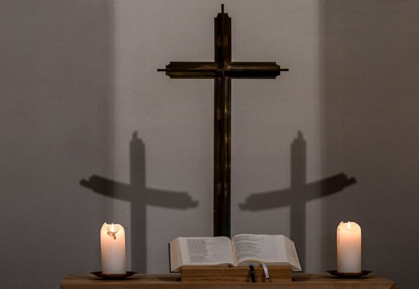 Ein Kreuz wirft in einer Kapelle seinen Schatten an die Wand. - © Jens Kalaene/dpa/Symbolbild