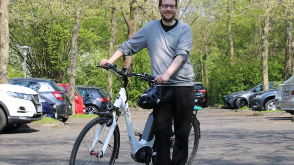 Klimaschutzmanager Lukas Menne steht mit seinem Dienstfahrrad auf dem Parkplatz vor dem Rathaus. Dass Parkfl&auml;chen zugunsten des Radverkehrs weichen m&uuml;ssen, ist nur eines seiner Themen. - &copy; Alexandra Schaller