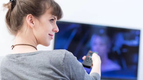 Eine Frau mit Fernbedienung vor dem Fernseher - &copy; Foto: Christin Klose/dpa-tmn