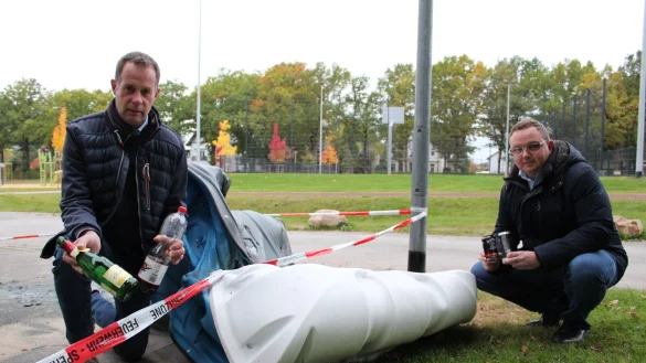 Klaus Hansen und Frederik Topp (von links) ist der Unrat am B&uuml;rgerpark ein Dorn im Auge. Die Reste eines j&uuml;ngst in Flammen aufgegangenen Dixie-Klos zeugen von Vandalismus. - &copy; Sandra Castrup