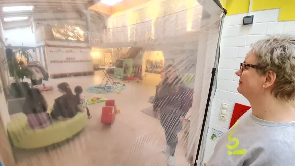 Hier ist die Grenze zur Baustelle: Teamleiterin Rike Vorher schaut aus der zur Zeit abgesperrten gelben Gruppe durch die Baufolie hinaus in die Eingangshalle, in der die Kinder toben. Auf der anderen Seite steht Kitaleiterin Lisa Frohböse. - © Marianne Schwarzer