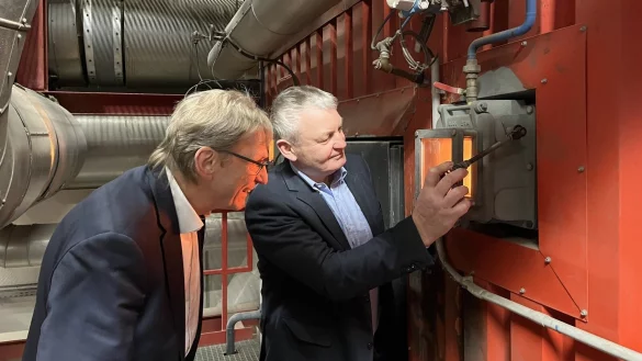Stadtwerke-Geschäftsführer Jörg Karlikowski (links) und Heinz-Josef Rodehuth schauen im Heizkraftwerk in Horn-Bad Meinberg ins Feuer - dort, wo die Resthölzer verbrannt werden. - © Jana Beckmann
