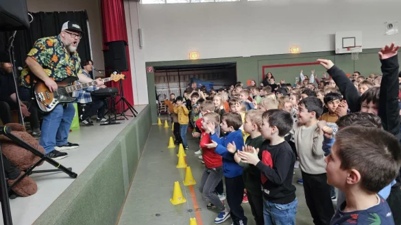 Sänger Sebastian Dold von der Band "Krawallo" macht die Ansagen und die Menge in der Turnhalle der Grundschule Ehrentrup macht mit. - © Astrid Sewing