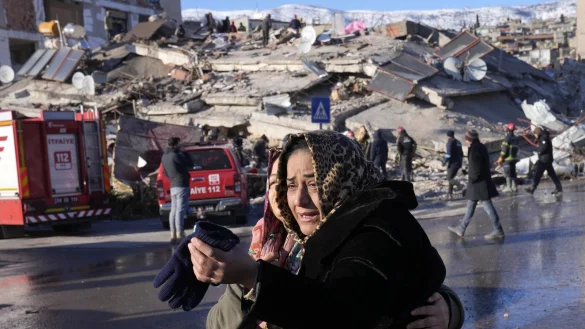 Zwei Frauen weinen vor einem zerst&ouml;rten Geb&auml;ude in Kahramanmaras. Im Hintergrund suchen Rettungskr&auml;fte nach &Uuml;berlebenden in den Tr&uuml;mmern. - &copy; dpa
