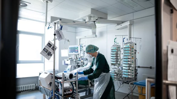 Eine Pflegekraft steht in einem Zimmer der Corona-Intensivstation und behandelt einen Patienten. - &copy; Fabian Strauch