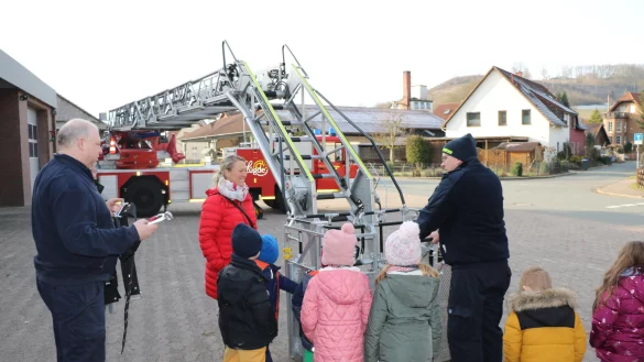 Dirk K&ouml;chling (links) und Maik Paskarbeit von der Feuerwehr L&uuml;gde haben die gro&szlig;e Leiter ausgefahren und den Kindern und Erzieherin Christina Schaper gezeigt, wie die Feuerwehrleute in gro&szlig;er H&ouml;he arbeiten und Menschen in einer speziellen Trage &uuml;ber die Leiter retten k&ouml;nnen. - &copy; Johanniter Lippe-H&ouml;xter