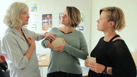 Dr. Doroth&eacute; D&uuml;pont (von links) erkl&auml;rt an einem Silikon-Tastmodell den beiden Besucherinnen Franziska Tilly und Sabrina Radde worauf es beim Abtasten der eigenen Brust im Rahmen einer Brustkrebs-Fr&uuml;herkennung ankommt. - &copy; Heidi Stork