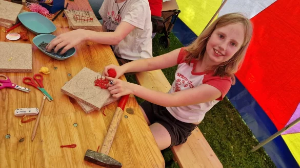 Die zehnjährige Jodie bespannt ein Nagelbrett mit Fäden. Am Ende soll eine Kirsche entstehen. - © Nadine Uphoff