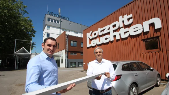 Verkaufsleiter Waldemar Balzer (links) und Firmenchef Majid Mirzaei stehen vor den Gebäuden mit dem bekannten Firmenschriftzug an der Lageschen Straße und zeigen eine Kotzolt-Leuchte. - © Jens Rademacher
