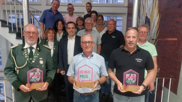 Hartmut Rissiek (vorne von links), Oberst des Sch&uuml;tzenvereins Harzberg-Glash&uuml;tte, Klaus Meier, Vorsitzender des F&ouml;rdervereins Sabbenhausen, und David L&ouml;dige, Schie&szlig;meister der Sch&uuml;tzenbruderschaft St. Kilian L&uuml;gde, nehmen im Beisein von B&uuml;rgermeister Torben Blome und Jury- und Vereinsmitgliedern die Heimatpreise entgegen. - &copy; Michaela Wei&szlig;e