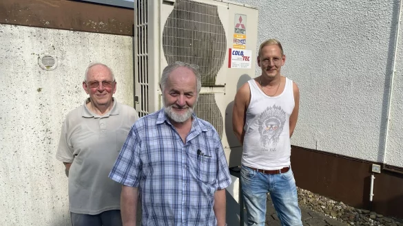 Karl-Heinz Isemann (v. l.), Detlef Reuter und Dominik Isemann vor der Wärmepumpe. Sie hat hohe Stromkosten verursacht. - © Dirk Windmöller