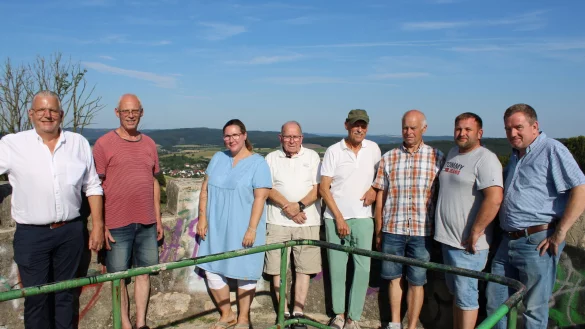 Klaus Meier (von links), Axel Kunze, Yvonne Eisenhauer, Ulrich Kollekowski, Wolfgang Blome, J&uuml;rgen M&uuml;ller, Bastian Homuth und Matthias M&uuml;ller zeigen auf dem Windm&uuml;hlenstumpf, welche Beeintr&auml;chtigungen sie durch die drei Anlagen bef&uuml;rchten. Im Hintergrund ist Sonneborn zu sehen. - &copy; Lorraine Brinkmann