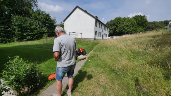 &Ouml;zt&uuml;rk Tayfun hat sich seinen Trimmer geschnappt und den Rasenm&auml;her vom Nachbarn geliehen, um dem Rasen rund um seinen Wohnblock einen ordentlichen Schnitt zu verpassen. Rechts sieht man noch, wie alles vorher aussah. - &copy; Jost Wolf