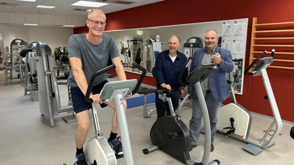 Christian Mönnink sitzt auf dem Ergometer in der Klinik Am Lietholz, wo er die Duale Reha absolviert hat - Chefarzt Dr. Jürgen Philipp (links) und der Ärztliche Direktor Jens Aron schauen zu. - © Alexandra Schaller