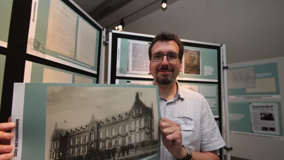 Stadtarchivar Marcel Oeben zeigt ein Foto von der Eröffnung des Lemgoer Krankenhauses im Jahr 1900, das in der Ausstellung im Hexenbürgermeisterhaus zu sehen ist. - © Jens Rademacher