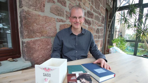 Philipp Schmidt-Rhaesa zeigt Buch, CD und Liederbuch zum 80. Geburtstag des 2015 verstorbenen Christof St&auml;hlin. Dieser leitete die einflussreiche Liedermacher-Schule "Sago". Der Name stand fr&uuml;her auf vielen K&uuml;chenschubladen - eine ist links im Bild zu sehen. - &copy; Jens Rademacher