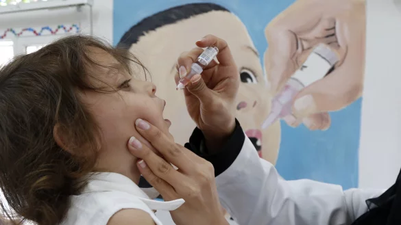 Ein medizinischer Mitarbeiter gibt einem Kind eine Dosis Polio-Impfstoff. - © picture alliance/dpa/XinHua