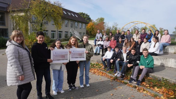 Die Sch&uuml;ler Lena (vorne stehend, von rechts), Jouline, Delin und Jonas &uuml;bergeben die Spende an Laura Hesse, Sprecherin des SOS-Kinderdorfes. - &copy; Michaela Wei&szlig;e