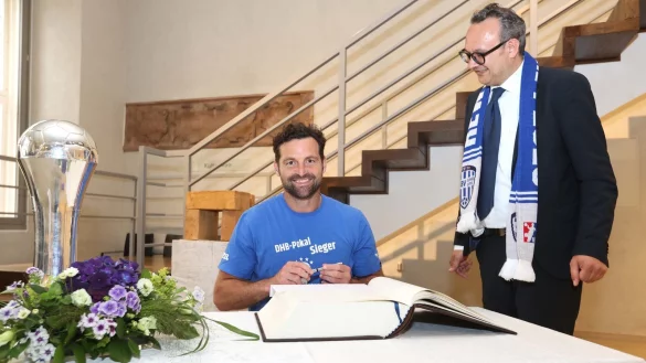 TBV-Trainer Florian Kehrmann tr&auml;gt sich ins Goldene Buch ein, B&uuml;rgermeister Markus Baier schaut ihm dabei &uuml;ber die Schulter. - &copy; TBV lemgo Lippe/Paul Cohen