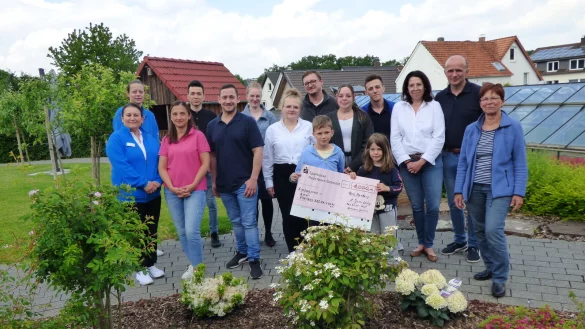 Scheck&uuml;bergabe in der Gartenanlage des Seniorenwohnsitzes Meinberger Hof: (von links) Nil&uuml;fer &Ouml;zkan, Vanessa Stein, Ali Rezali, Zeynep &Ouml;tzt&uuml;rk, Jilia B&uuml;low, Benjamin Kloss, Alexander Martin, Rene Schweizer, Melssa Ehlert, Arne Gerlach, Anke Wortmann-Gerlach und Britta Stolp sowie (vorn mit Scheck) Maximilian und Liciana Gerlach. - &copy; Peter Radszuweit