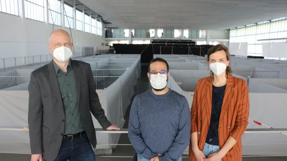 Integrationskoordinator Stefan Fenneker (links), Organisator Samer Chtewi vom Arbeiter-Samariter-Bund und Tabea Beer von der st&auml;dtischen Kontaktstelle f&uuml;r Ausl&auml;nderinnen und Ausl&auml;nder stehen in der vorbereiteten Halle. - &copy; Janet K&ouml;nig