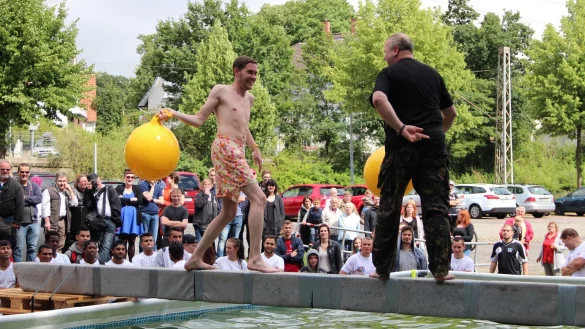 Hau drauf: Bei der Disziplin &bdquo;Pool-Kloppe&ldquo; balancieren die Wettkampf-Teilnehmer vor den Augen zahlreicher Hafenfest-Besucher auf einem Balken, um sich gegenseitig mit einem H&uuml;pfball ins k&uuml;hle Nass zu bef&ouml;rdern. FOTO: STORK - &copy; Heidi Stork